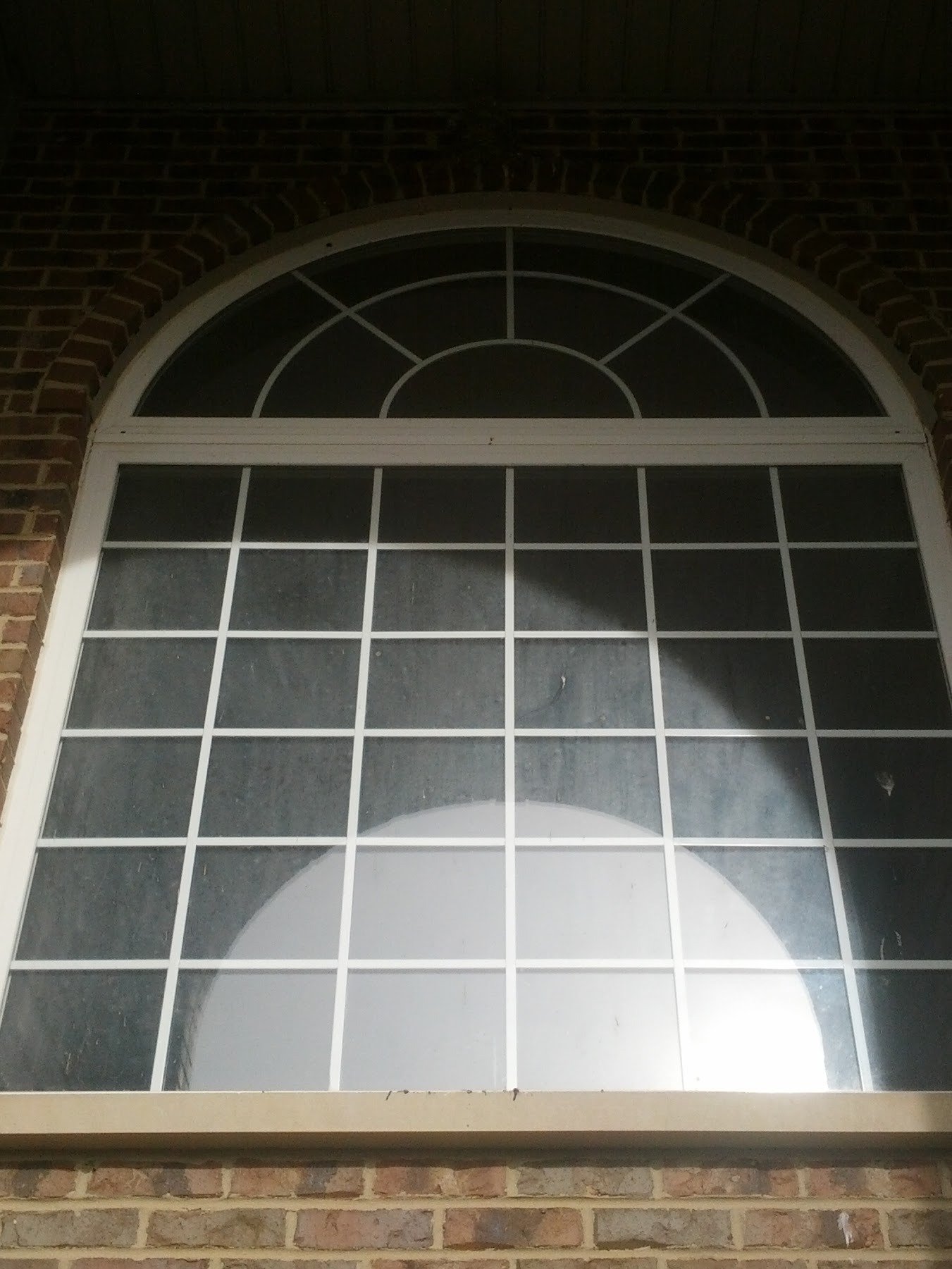 Dirty arched foyer window before professional cleaning