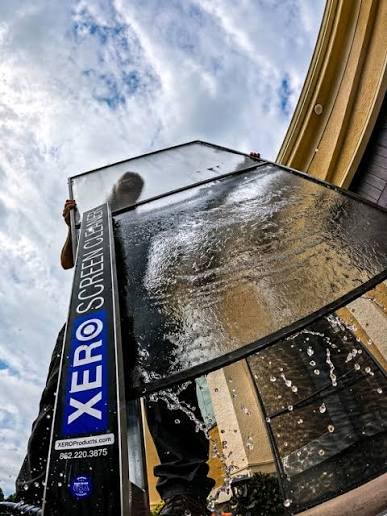 Technician cleaning an elevated window screen with the XERO screen cleaning system